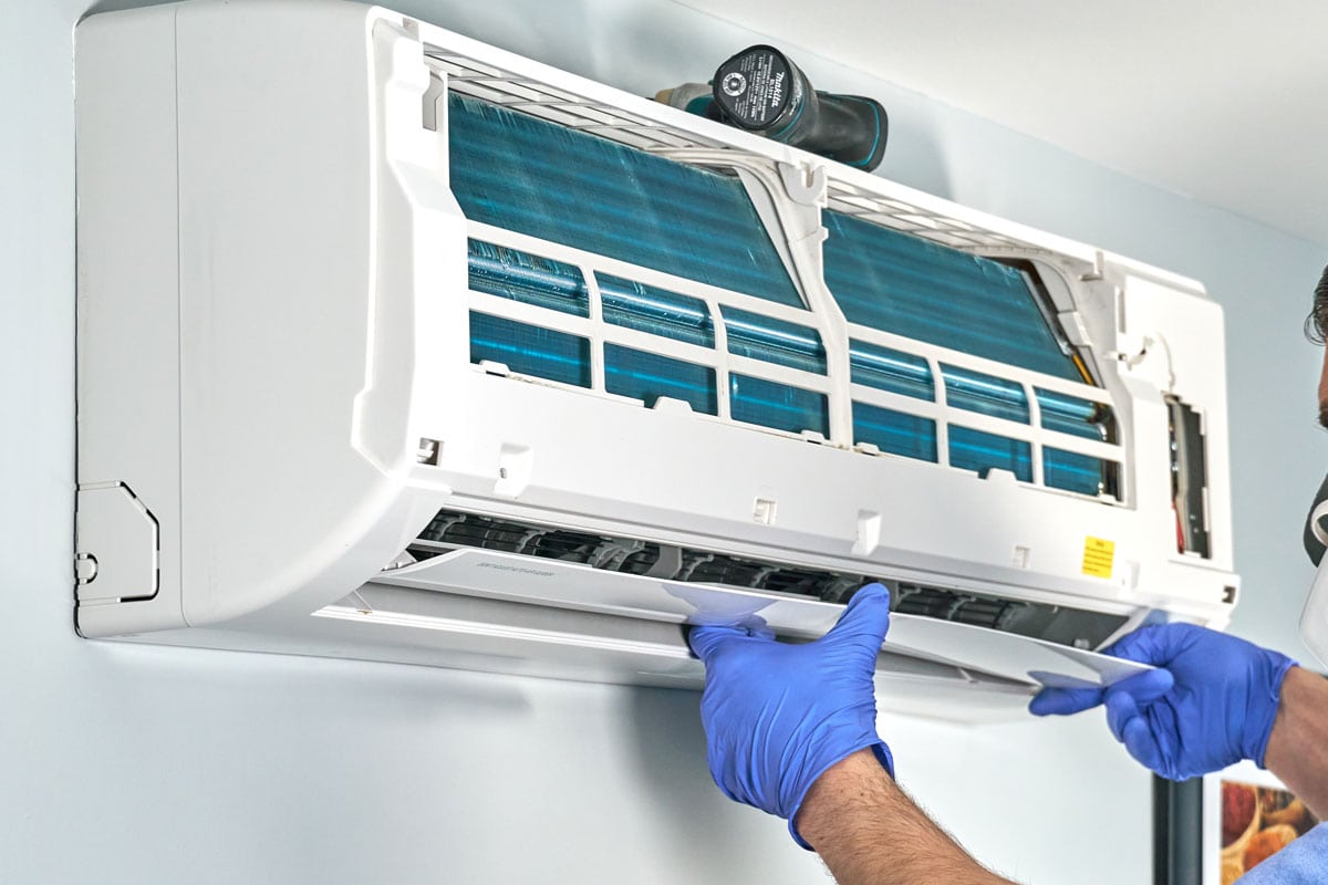 Technician-in-blue-gloves-and-mask-disassembling-air-conditioner-and-preparing-it-for-cleaning-air-conditioners-help-to-avoid